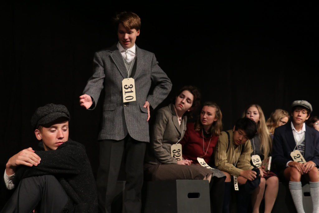 Several students on stage in costume performing in play