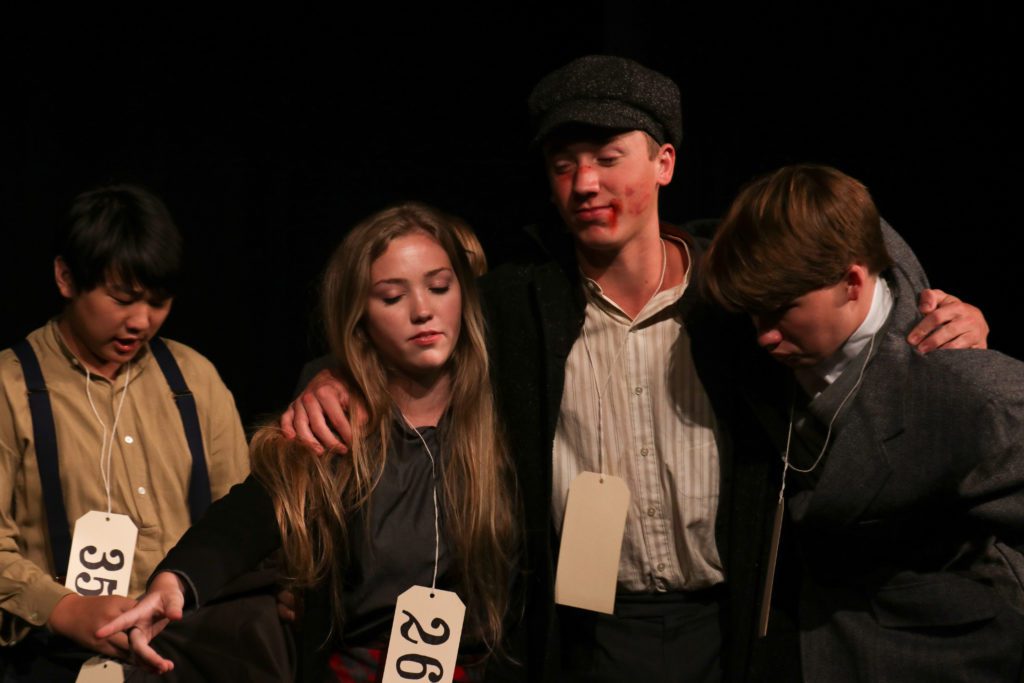 four students on stage for theatre performance
